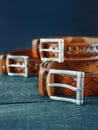 Three leather brown belts on dark background