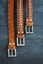 Three leather brown belts on dark background