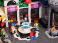 Three Lego child minifigures standing around a fountain in the city square