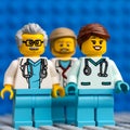 Three Lego doctor minifigures standing against a blue baseplate background