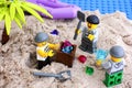 Three Lego robbers digging out box of gems on island