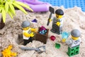 Three Lego robbers digging out box of gems from sand on the island
