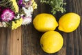 Three Lemons and Flowers on Rustic Wooden Background