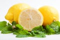 Three lemons on fresh lemon balm leaf on white background