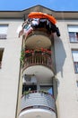 Three levels of rounded balconies secured with red metal fence filled with flowers and clothes drying