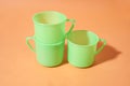 Three light green plastic glasses are on an orange background Royalty Free Stock Photo