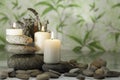 Three lighted candles on river pebbles with lavender on herbal background