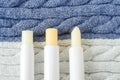 Three lip balms on a knitted background. Winter lip care sticks with beeswax, honey, panthenol and shea butter.