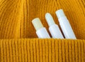 Three lip balms on an orange knitted background. Winter lip care sticks with beeswax, honey, panthenol and shea butter.