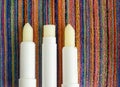 Three lip balms, sunscreen sticks on the colorful beach towel. Summer lip treatment and UV protection. Close up, flat lay