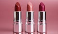 Three lipsticks are lined up on a pink background Royalty Free Stock Photo