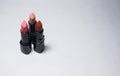 Three lipsticks stand vertically on a white background close to each other in the left side