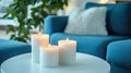 Three lit candles on a white table in a cozy living room with a blue sofa and plants Royalty Free Stock Photo