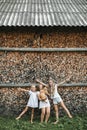 Three little cheerful girls, sisters, playing with red cat in the yard outdoors in summer, standing over the background Royalty Free Stock Photo