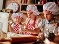 Three little chefs enjoying in the kitchen making cakes. Girls at the kitchen. Family housekeeping