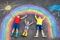 Three little children, two school kids boys and toddler girl having fun with with rainbow picture drawing with colorful Royalty Free Stock Photo