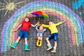 Three little children, two school kids boys and toddler girl having fun with with rainbow picture drawing with colorful Royalty Free Stock Photo