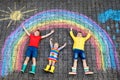 Three little children, two school kids boys and toddler girl having fun with with rainbow picture drawing with colorful Royalty Free Stock Photo