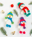 Three Little cute crocheted snowmans in a multicolor hats and scarfs on a white wooden background