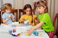 Three little girls painting on Easter eggs