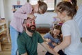 Three little girls putting on make up on their father, fathers day with daughters at home.