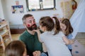 Three little girls putting on make up on their father, fathers day with daughters at home.