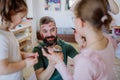 Three little girls putting on make up on their father, fathers day with daughters at home.