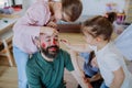 Three little girls putting on make up on their father, fathers day with daughters at home.