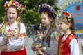 Three little girls in Ukrainian traditional embroidery costumes singing during concert devoted to the Remembrance Day