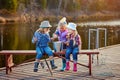 Three little happy girls brag about fish caught on a fishing pole. Fishing from a wooden pontoon. Royalty Free Stock Photo