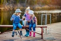 Three little happy girls brag about fish caught on a fishing pole. Fishing from a wooden pontoon