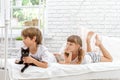 Three little happy kids playing with cat on white bed at h Royalty Free Stock Photo