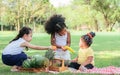 Three little mixed race kid girls smiling with happiness, fun amusement, playing, sitting for picnic and eating piece of