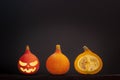 Three little pumpkins with halloween face lie in a line on a gray background
