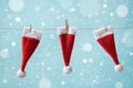 Three little Santa Claus hat hanging on a string against blue snowy background. Christmas and New year concept. Greeting card