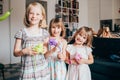 Three little sisters indoor at home playing with balloon looking camera smiling Royalty Free Stock Photo