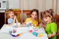 Three little sisters painting Easter eggs