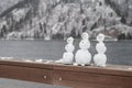 Three little snowmen standing on the railing. River embankment in winter, the river is not frozen. Copy space. Royalty Free Stock Photo