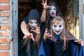 Three little teenage girls in zombie costumes go out the door of an old ruined building and look frighteningly at the camera. Royalty Free Stock Photo