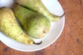 Three long ripe green pears on white pale top view closeup
