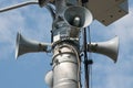 Three loudspeakers on pole against blue sky