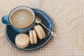 Three macaroni cake and a cup of coffee on a beige polka dot background. Top view