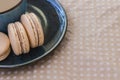 Three macaroni cake and a cup of coffee on a beige polka dot background. Top view