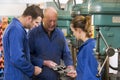 Three machinists in workspace by machine talking Royalty Free Stock Photo