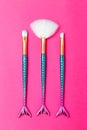 Three makeup brushes mermaid tail on a bright pink background. Vertical