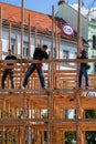 Three male carpenters building a wooden frame structure in Prague.