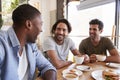 Three Male Friends Meeting For Lunch In Coffee Shop Royalty Free Stock Photo