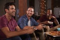 Three male friends playing video games looking at each other Royalty Free Stock Photo