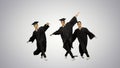 Three male graduates in robes and mortarboards dancing in synch Royalty Free Stock Photo