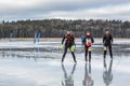 Three male ice skaters on wet watery and frozen lake.